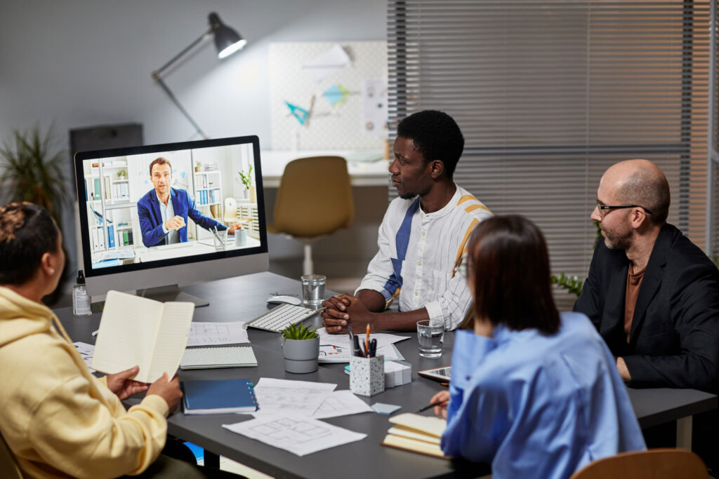 employees gathered around a monitor for a video conference